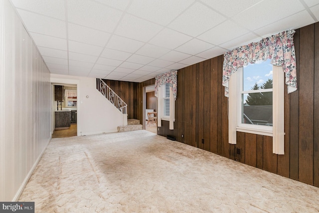 interior space featuring carpet flooring, a paneled ceiling, and wooden walls