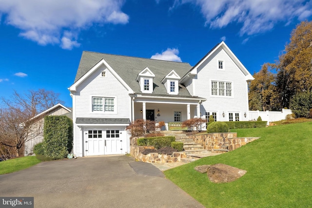 view of front of home with a garage, aphalt driveway, fence, a porch, and a front yard