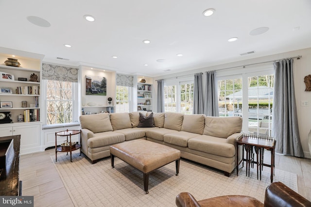 living room with recessed lighting, visible vents, built in features, and ornamental molding