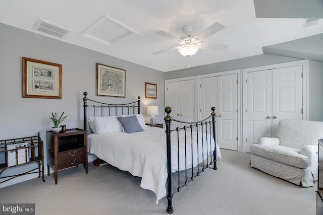 bedroom featuring light carpet, attic access, visible vents, and two closets