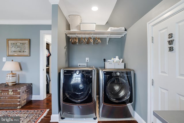 clothes washing area with laundry area, baseboards, wood finished floors, crown molding, and washer and dryer