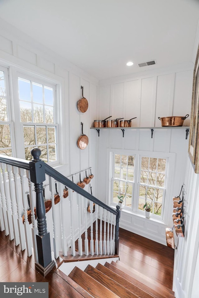 stairway with visible vents, a decorative wall, and wood finished floors