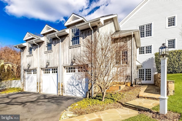 multi unit property featuring a garage, french doors, board and batten siding, and aphalt driveway