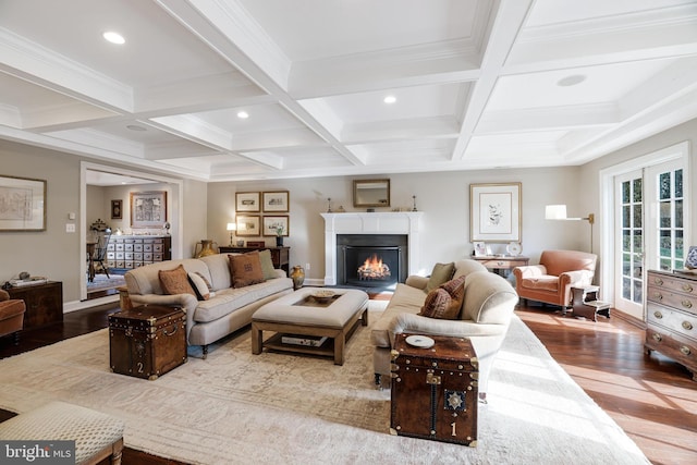 living area with a lit fireplace, beam ceiling, and wood finished floors