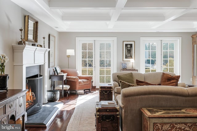 living area featuring a warm lit fireplace, dark wood-type flooring, coffered ceiling, french doors, and beam ceiling