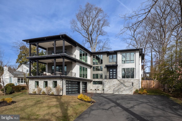 view of front of home featuring a garage, a balcony, ceiling fan, and a front lawn