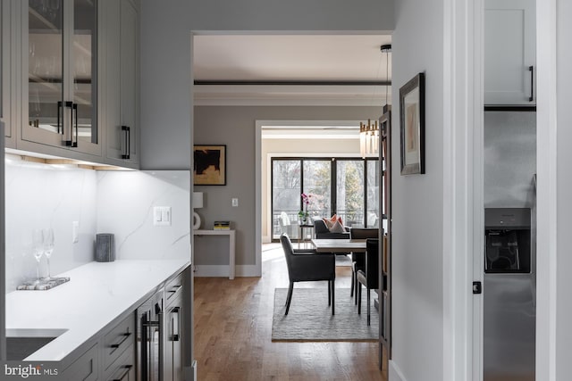 kitchen featuring gray cabinets, hanging light fixtures, backsplash, light stone counters, and wood-type flooring