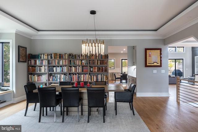 dining area with light hardwood / wood-style floors and a raised ceiling