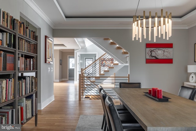 dining space featuring a raised ceiling, crown molding, and light hardwood / wood-style flooring