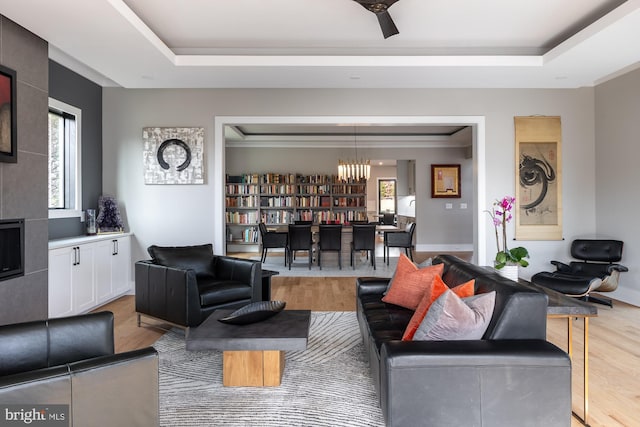 living room with plenty of natural light, a tray ceiling, and light wood-type flooring