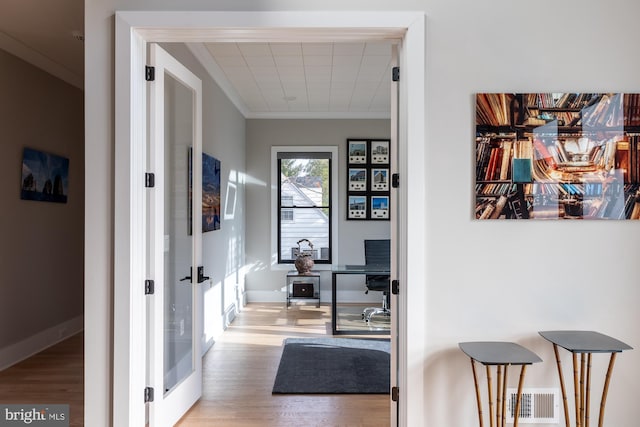 hall with crown molding, french doors, and light wood-type flooring