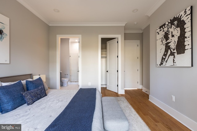 bedroom featuring hardwood / wood-style floors, crown molding, and ensuite bath