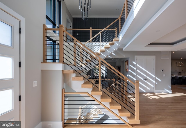 stairway with hardwood / wood-style floors and a high ceiling