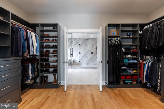 walk in closet with light hardwood / wood-style floors