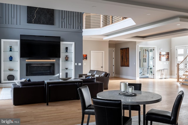 dining room featuring a raised ceiling, a large fireplace, and light hardwood / wood-style floors