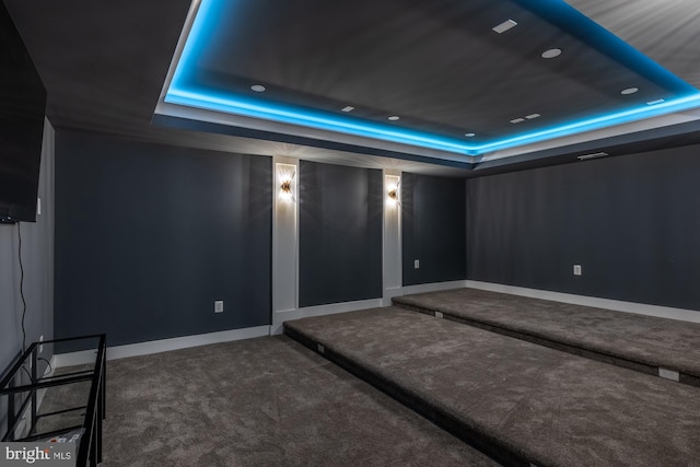 home theater room with a tray ceiling and carpet floors