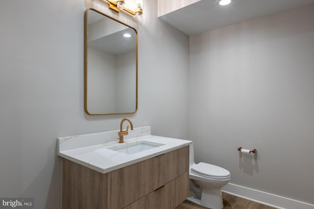 bathroom featuring vanity, wood-type flooring, and toilet