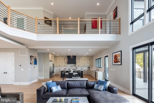 living room featuring sink, a high ceiling, light hardwood / wood-style flooring, and a wealth of natural light