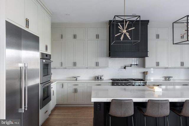 kitchen featuring a breakfast bar, light stone counters, appliances with stainless steel finishes, decorative backsplash, and white cabinets