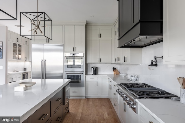 kitchen featuring white cabinetry, light stone counters, pendant lighting, and stainless steel appliances