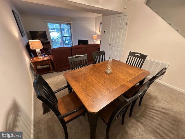 carpeted dining area featuring a large fireplace