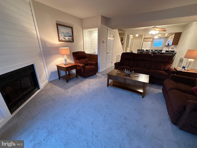 carpeted living room with a fireplace and ceiling fan