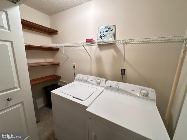 washroom featuring separate washer and dryer, tile patterned flooring, and a textured ceiling