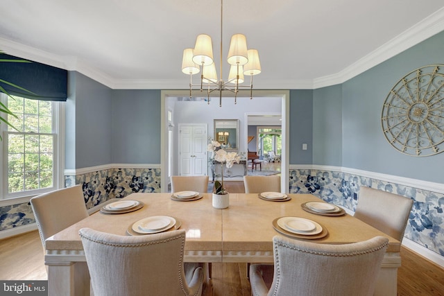 dining space featuring crown molding, a notable chandelier, and wood finished floors