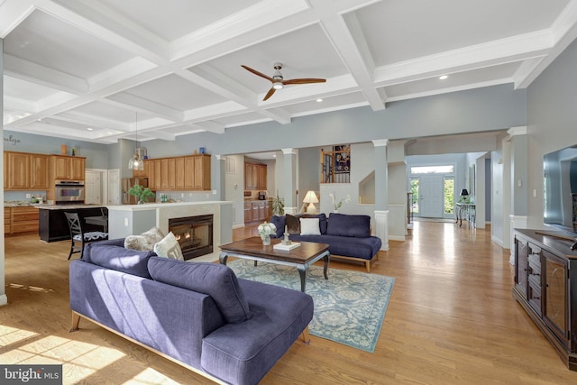 living area featuring decorative columns, coffered ceiling, beamed ceiling, a ceiling fan, and light wood-type flooring