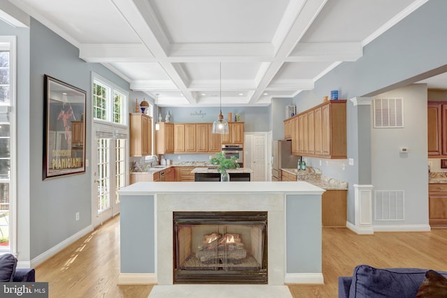 kitchen featuring light countertops, beam ceiling, a kitchen island, light wood-style flooring, and stainless steel fridge with ice dispenser