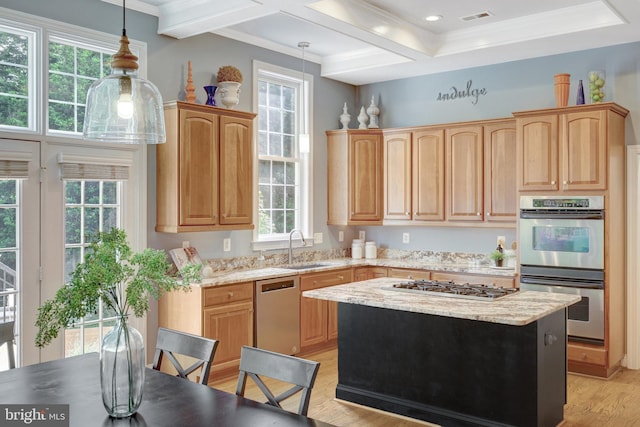 kitchen featuring appliances with stainless steel finishes, crown molding, a center island, light wood-style floors, and a sink