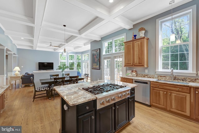kitchen featuring appliances with stainless steel finishes, a sink, light wood-style flooring, beam ceiling, and pendant lighting