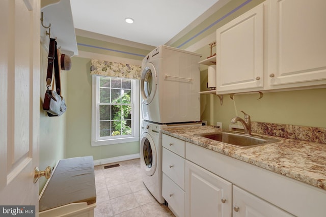 laundry room featuring stacked washer / dryer, cabinet space, light tile patterned floors, baseboards, and recessed lighting