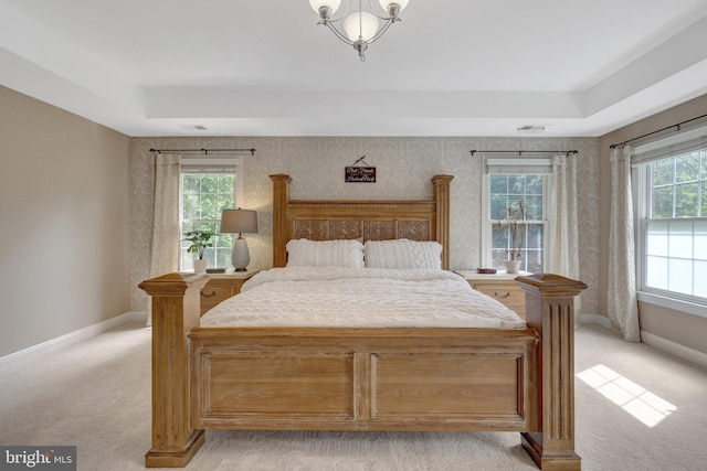 bedroom with light colored carpet, baseboards, and a tray ceiling