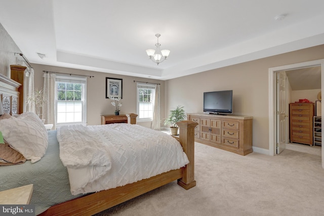 bedroom featuring a tray ceiling, light carpet, and multiple windows