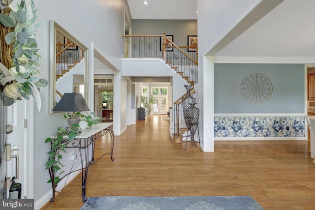 entryway featuring stairway, baseboards, wood finished floors, a high ceiling, and crown molding