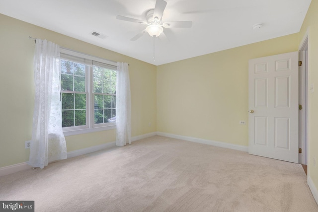 empty room featuring light colored carpet, ceiling fan, and baseboards