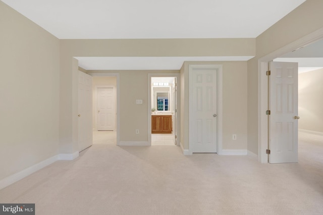 spare room featuring light carpet and baseboards