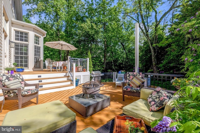 wooden terrace with an outdoor living space with a fire pit and grilling area