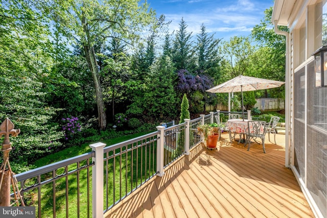 wooden deck featuring outdoor dining area and view of scattered trees