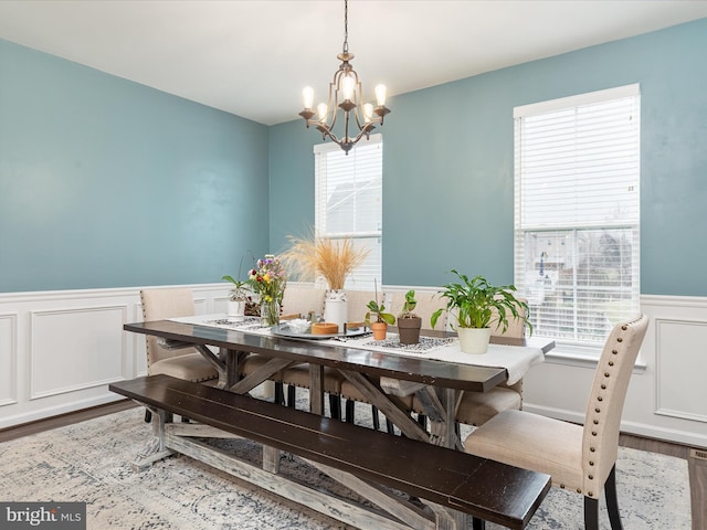 dining space with wood-type flooring, plenty of natural light, and a chandelier