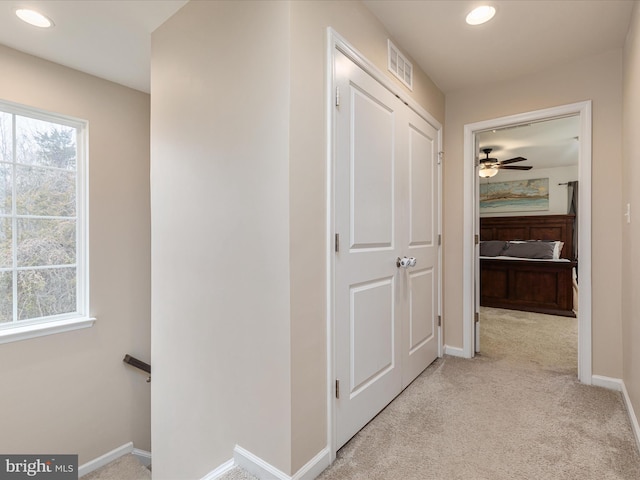 corridor featuring light colored carpet and a wealth of natural light