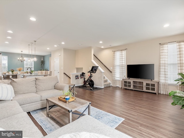 living room with a healthy amount of sunlight, sink, hardwood / wood-style floors, and a notable chandelier