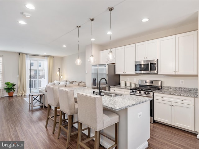 kitchen with a breakfast bar, sink, appliances with stainless steel finishes, an island with sink, and white cabinets