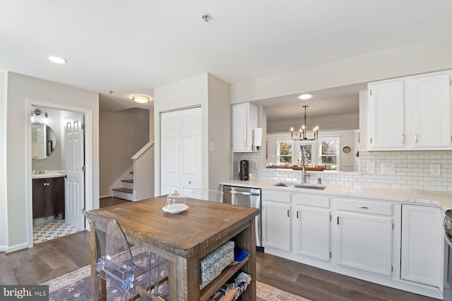 kitchen featuring decorative backsplash, dishwasher, dark wood-type flooring, white cabinetry, and a sink