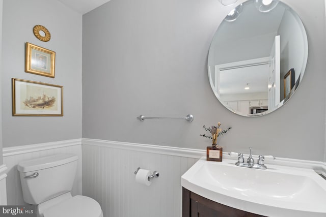 bathroom featuring a wainscoted wall, vanity, and toilet