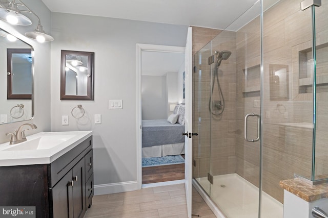 ensuite bathroom with baseboards, connected bathroom, a shower stall, and vanity