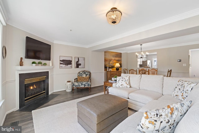 living room featuring crown molding, a fireplace with flush hearth, wood finished floors, visible vents, and an inviting chandelier