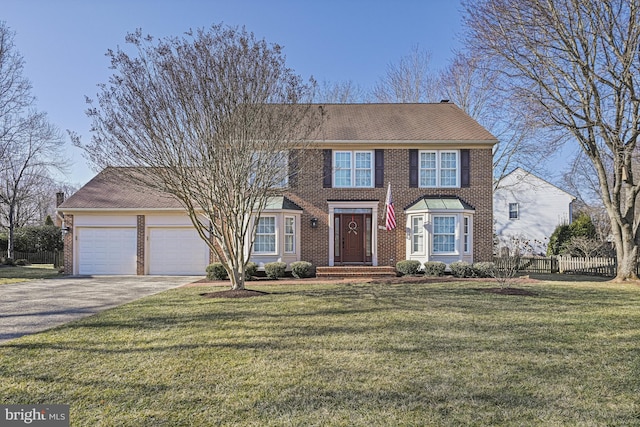 colonial home featuring a garage, brick siding, fence, and driveway