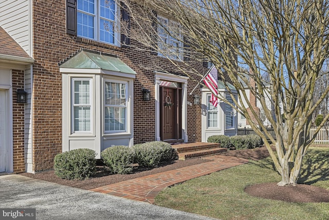 property entrance featuring brick siding and fence